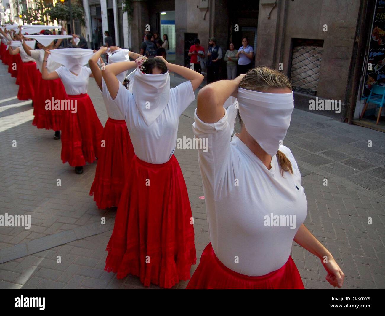 Girls covering their faces with white scarves when women from 'Red Tide' activist group performing in red skirts in the street of Lima as part of the activities of the International Day for the Elimination of Violence against Women, an event that is commemorated annually on November 25, the date on which the three Mirabal sisters (Patria, Minerva and María Teresa) were murdered. in the Dominican Republic on 1960. Credit: Fotoholica Press Agency/Alamy Live News Stock Photo