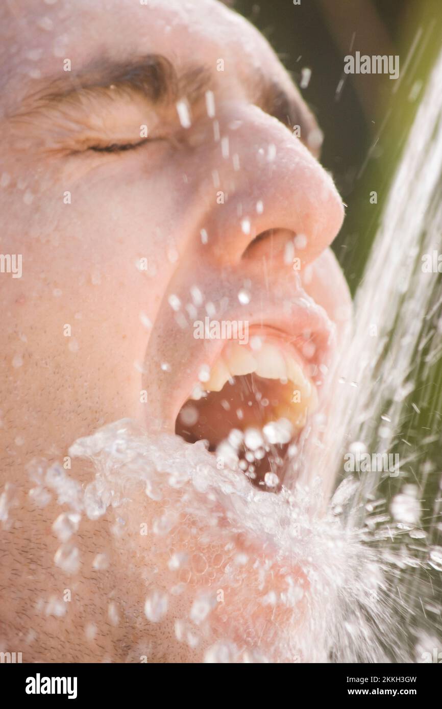 Man Splashes Down A Mouthful Of Water From A Pouring Tap Stock Photo