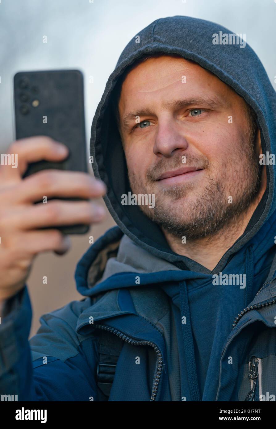 Hiker In Cold Weather Taking Photos With His Smart Phone Stock Photo
