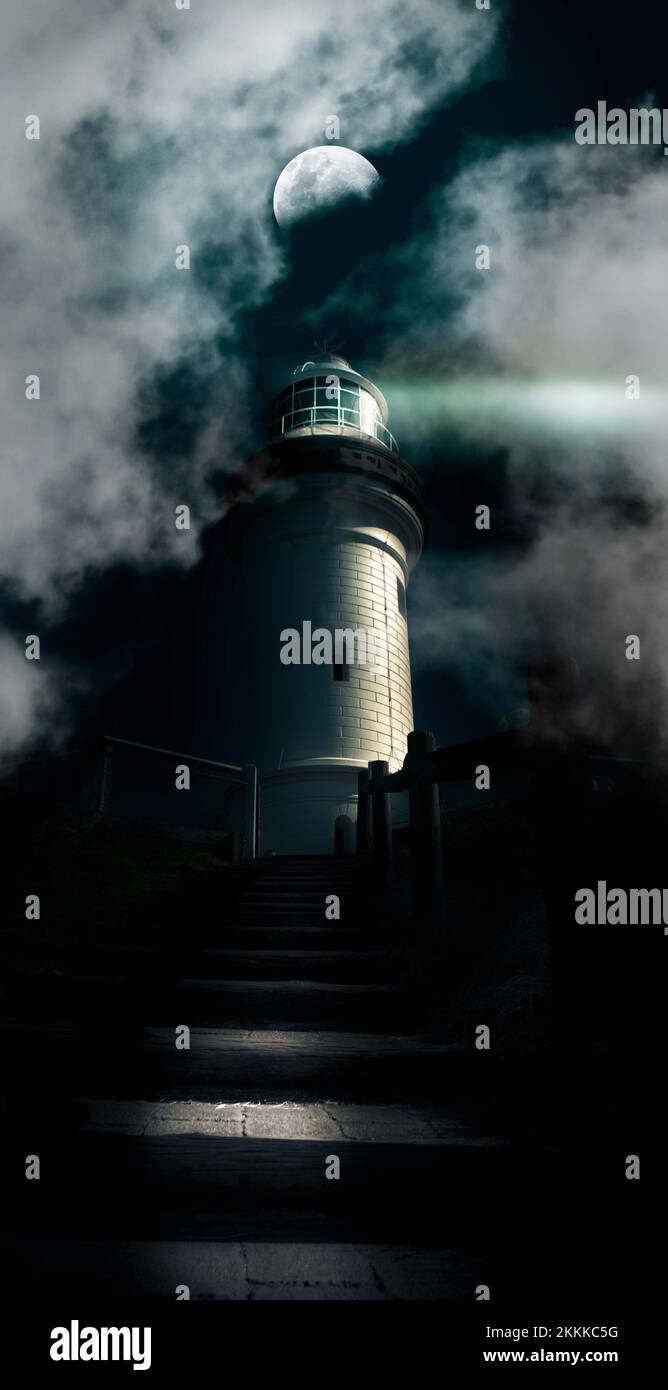 Dark Atmospheric Lighthouse Shining A Beacon Off Into The Night Mist And Fog In A Storm Warning Of Dangerous Weather Conditions, Cape Byron Lighthouse Stock Photo