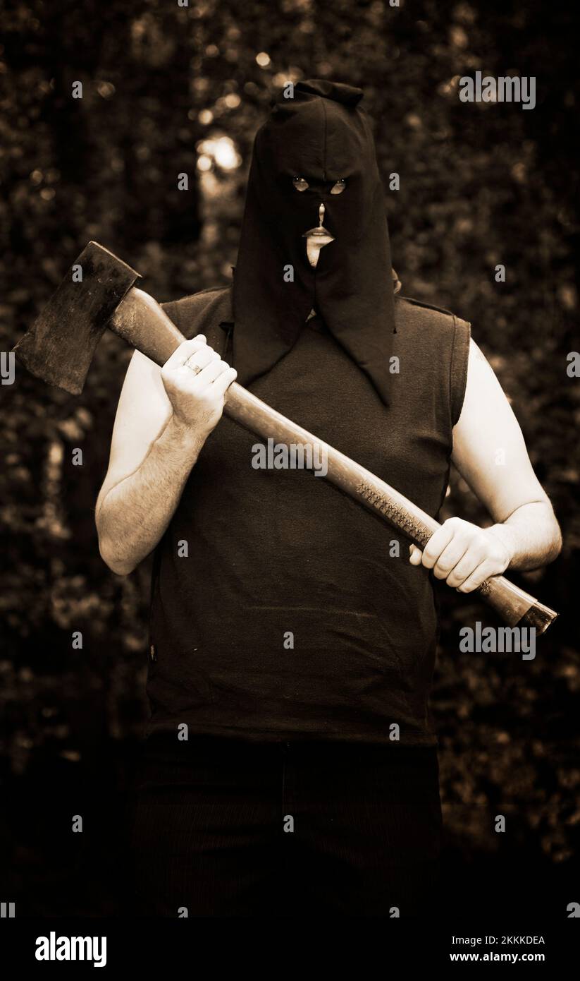 Hooded Medieval Executioner With Axe Trees In Background Stock Photo