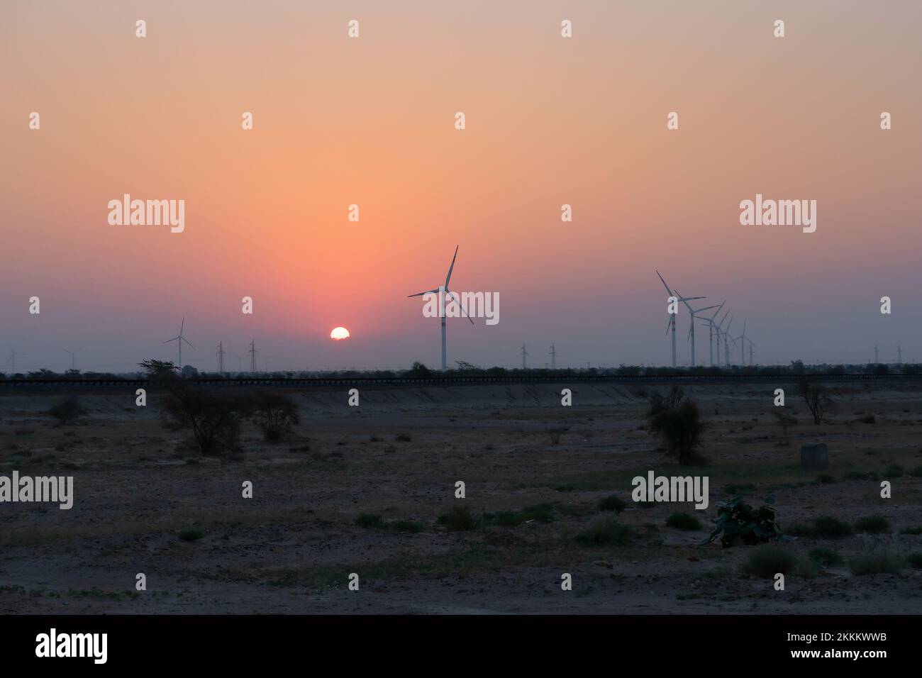 Dawn light in desert sky with Electrical power generating wind mills producing alterative eco friendly green energy for consumption by local people. S Stock Photo