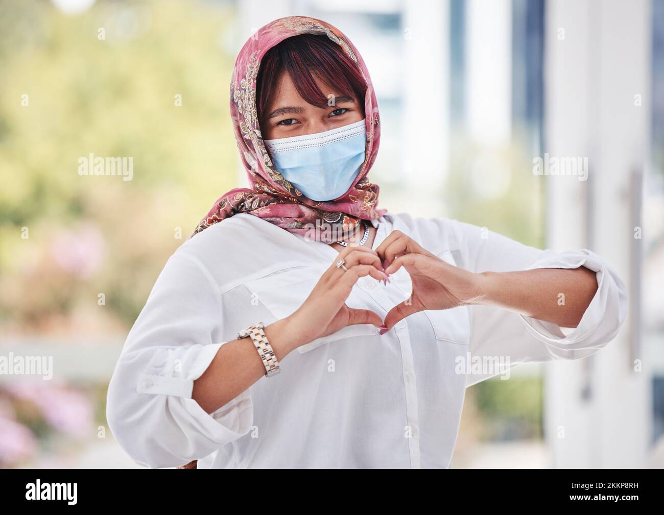 Muslim, woman with hijab and covid, face mask with hand heart in city portrait, health and love outdoor. Compliance, hands and healthcare with safety Stock Photo