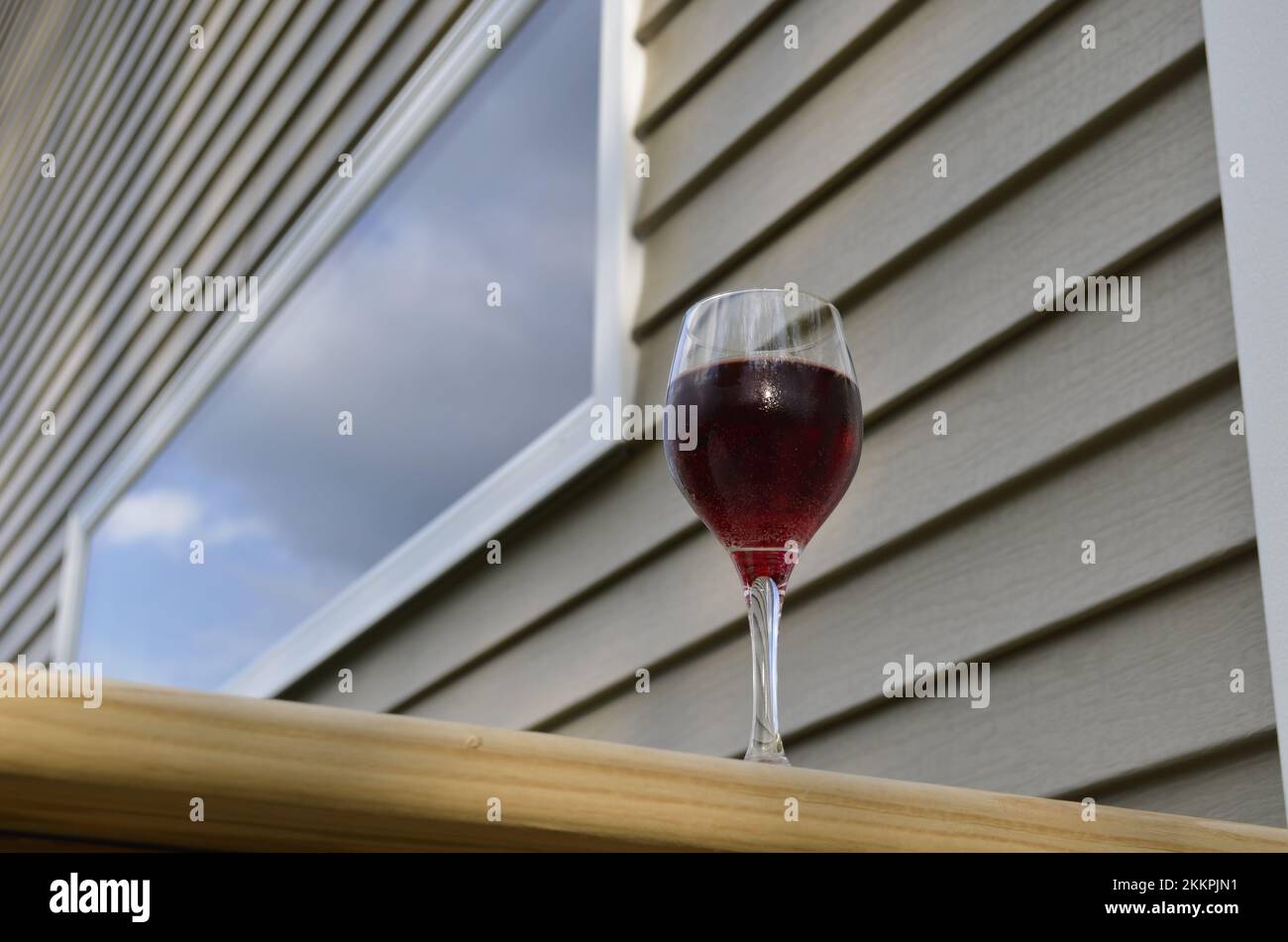 Red wine in a glass on a wooden railing Stock Photo