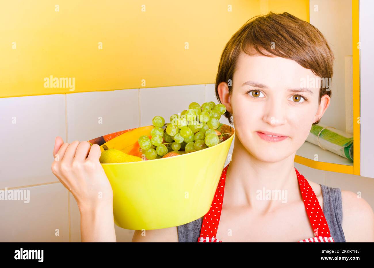 Lovely young woman holding a healthy bowl of fresh fruit salad indoors Stock Photo
