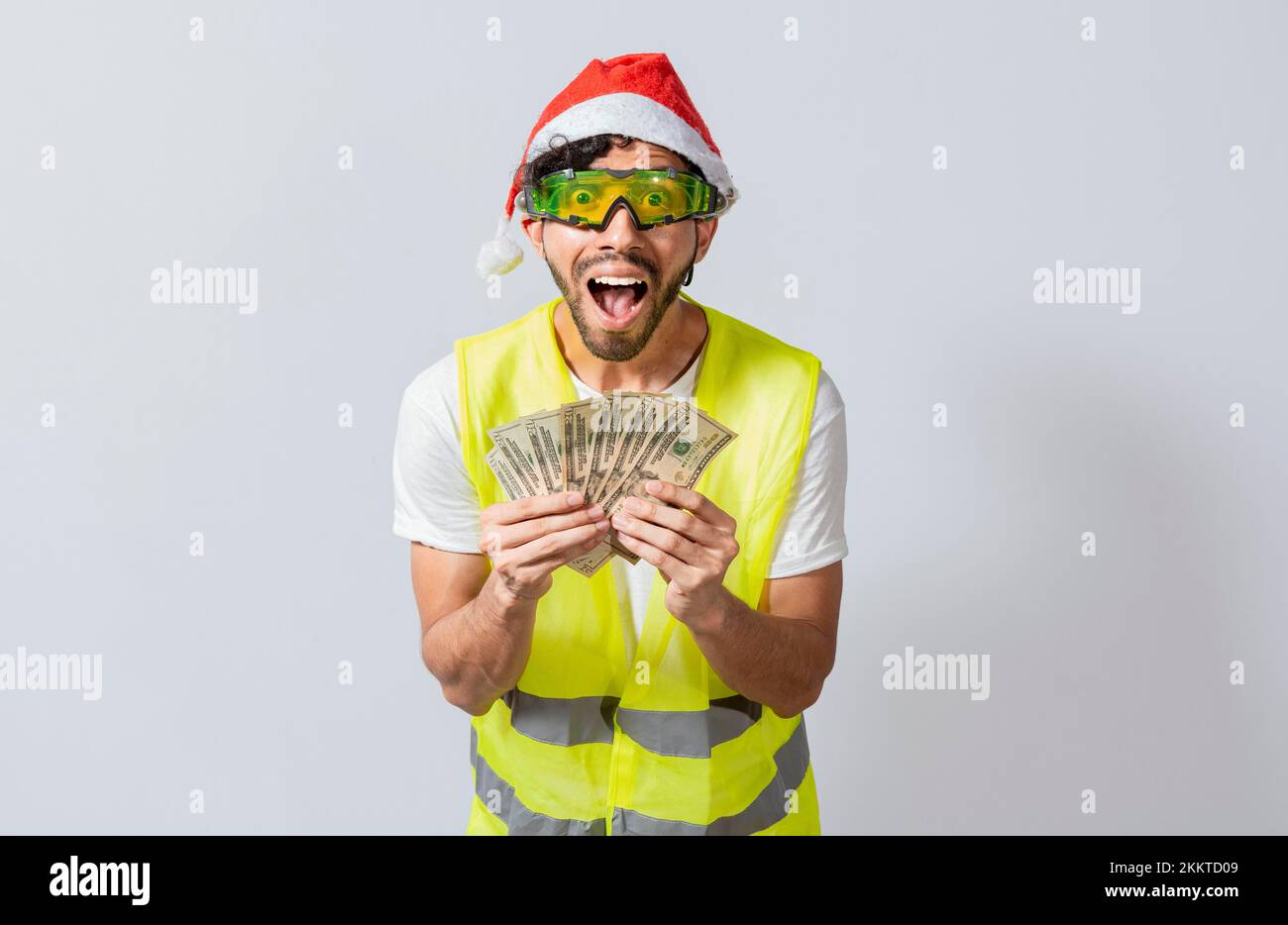 Engineer in christmas hat holding money smiling at camera. builder engineer in christmas hat with happy expression holding dollars isolated. Concept o Stock Photo