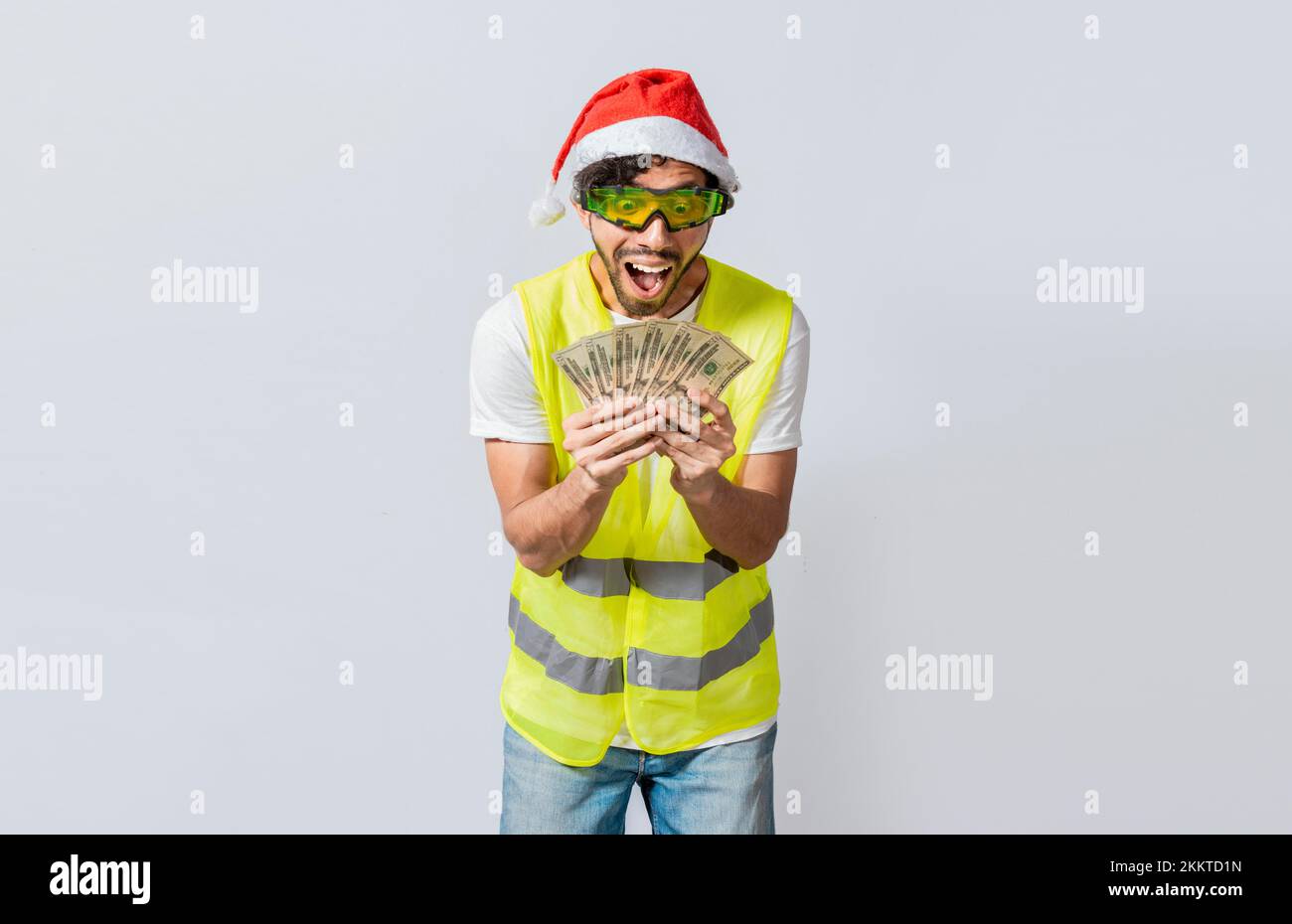 Builder engineer in christmas hat with happy expression holding dollars isolated. Concept of engineer with money in holiday season, Engineer in christ Stock Photo
