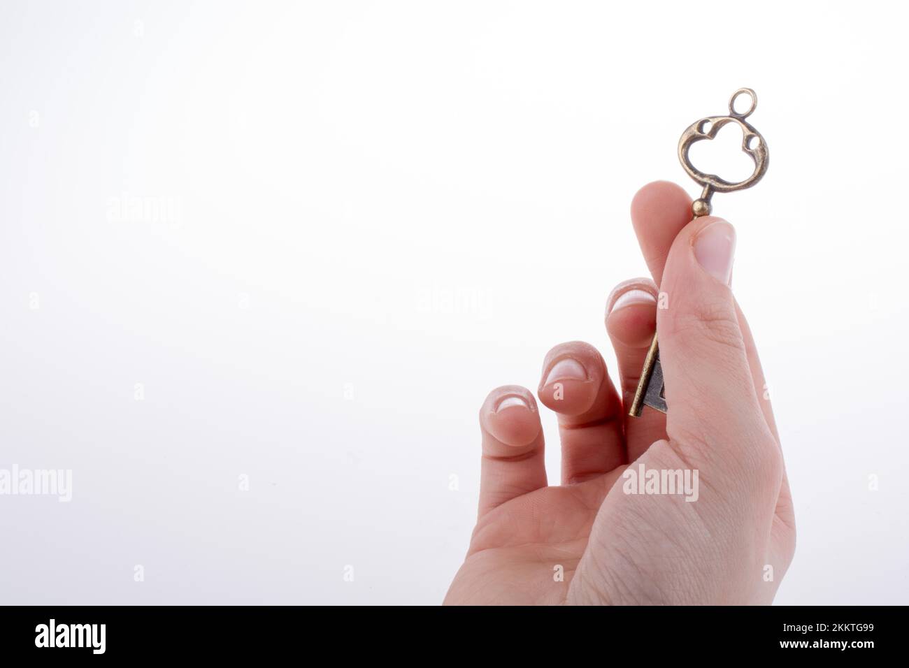 Hand holding a retro styled metal key on a white background Stock Photo ...