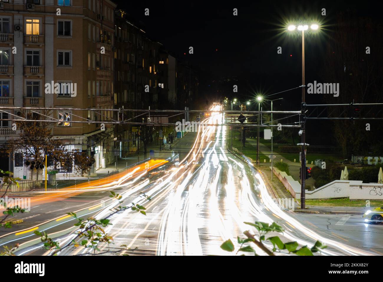 Night scene of tram in traffic at crossing with lighttrail Stock Photo