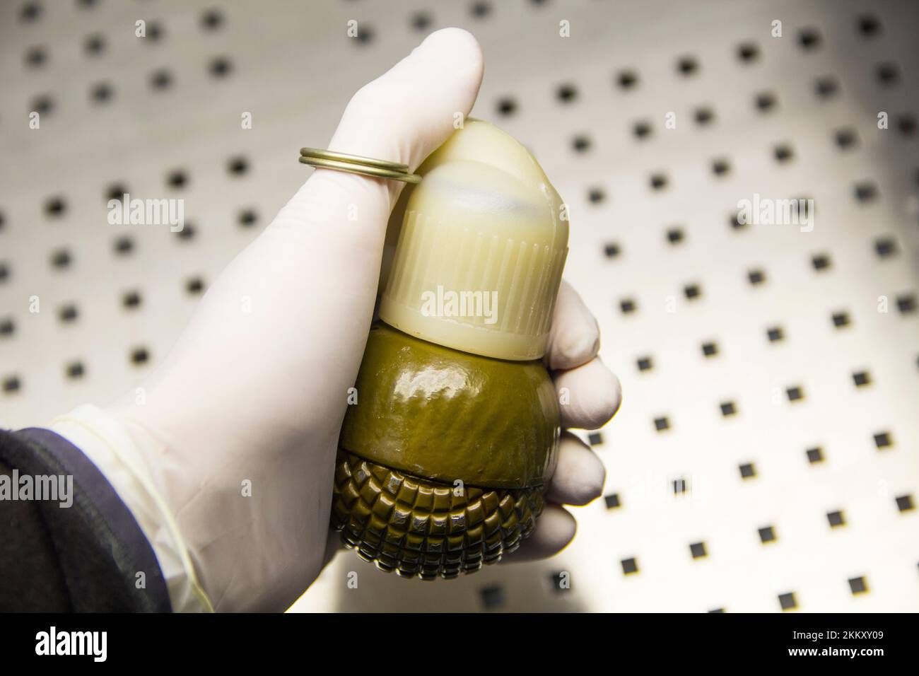 Male hand in a rubber glove holds a grenade close-up Stock Photo