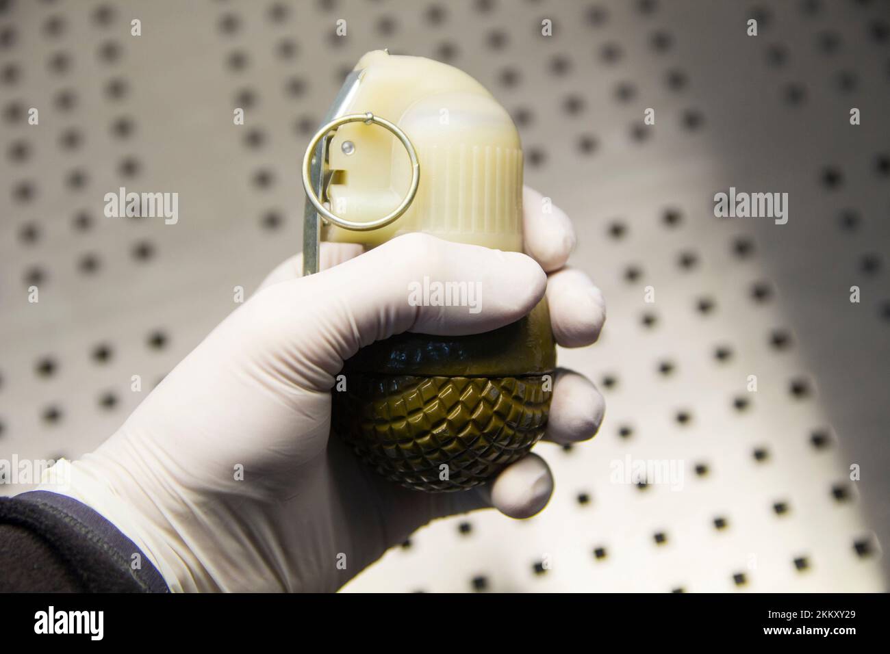 Male hand in a rubber glove holds a grenade close-up Stock Photo