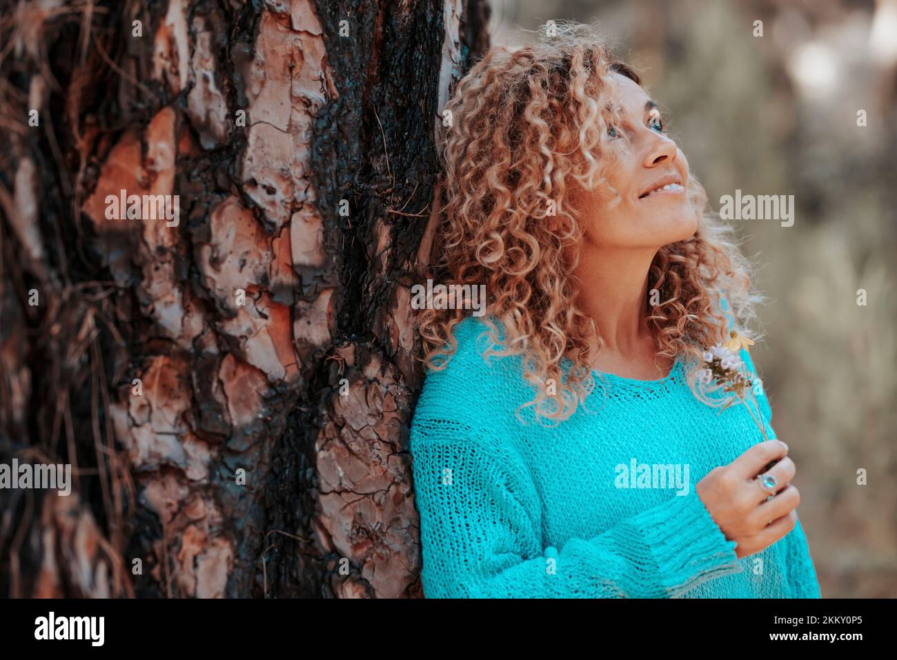 Side view of happy beautiful woman enjoying nature and outdoor leisure activity alone looking and admiring trees. Big old trunk pine and people loving Stock Photo