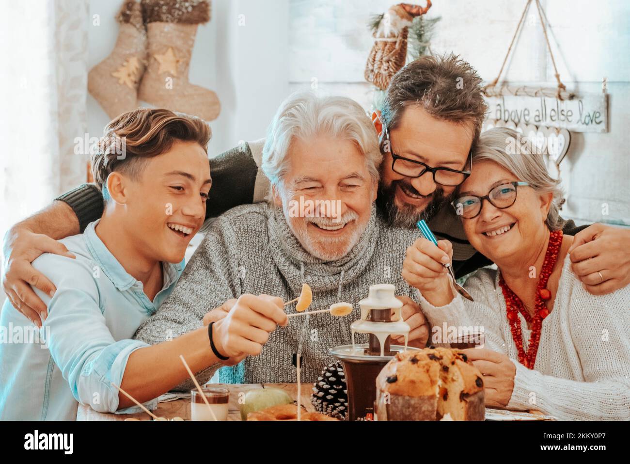 Family group celebrate together christmas lunch at the table eating and having fun in friendship. Mixed ages men and woman people enjoying holiday xma Stock Photo