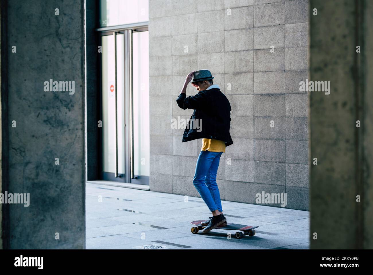 Green transport alternative young using skate board in the city between grey urban wall to move and go. Copy space and concept of outdoor leisure acti Stock Photo