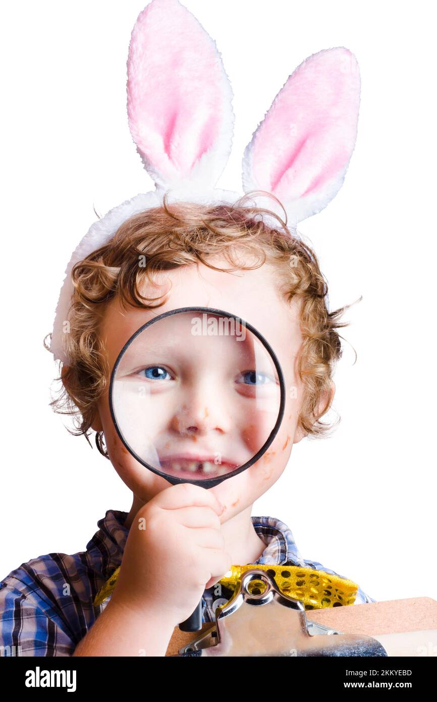 Cute young boy with rabbit ears looking through magnifying glass