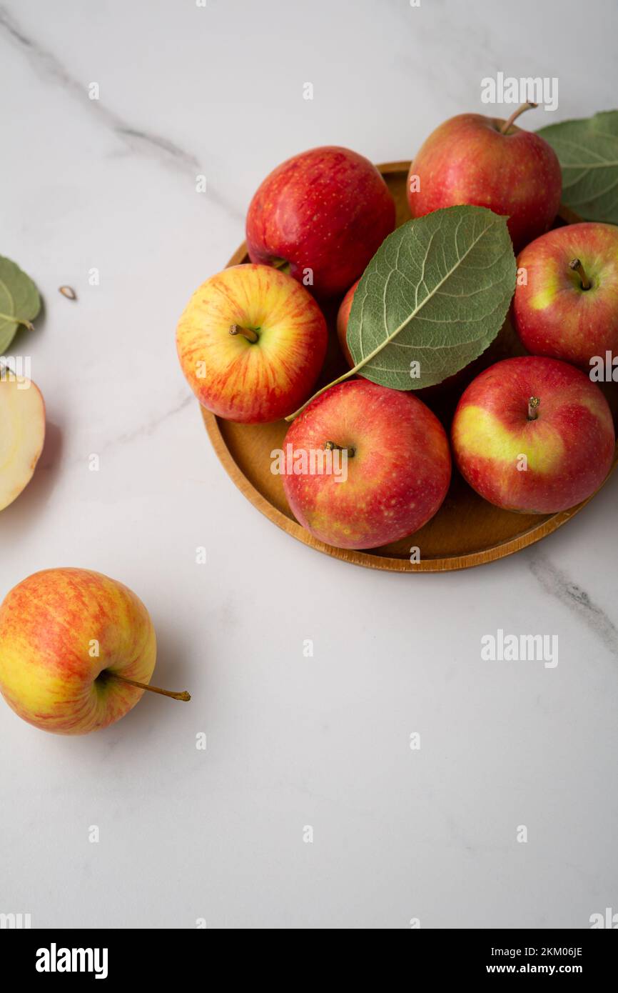Fresh red and yellow apples on plate healthy food on light surface Stock Photo
