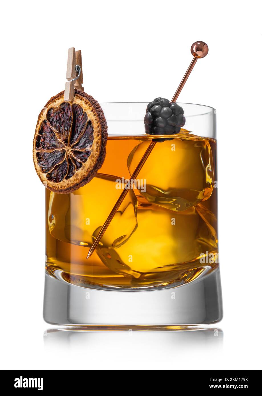 Old fashioned whiskey cocktail with dry orange and blackberry and large ice cubes on white Stock