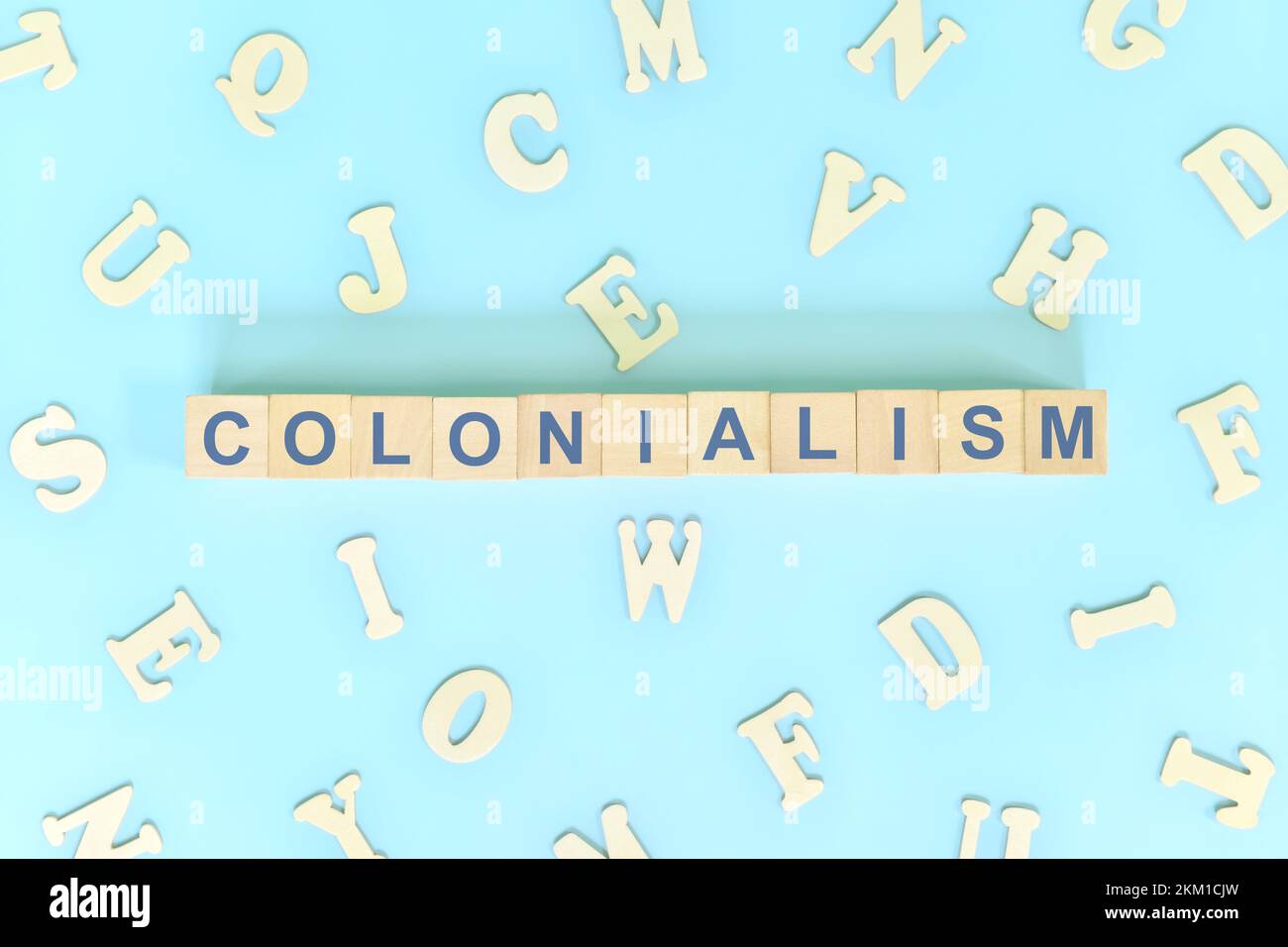 Colonialism government, politics and history concept. Wooden blocks typography flat lay in blue background. Stock Photo