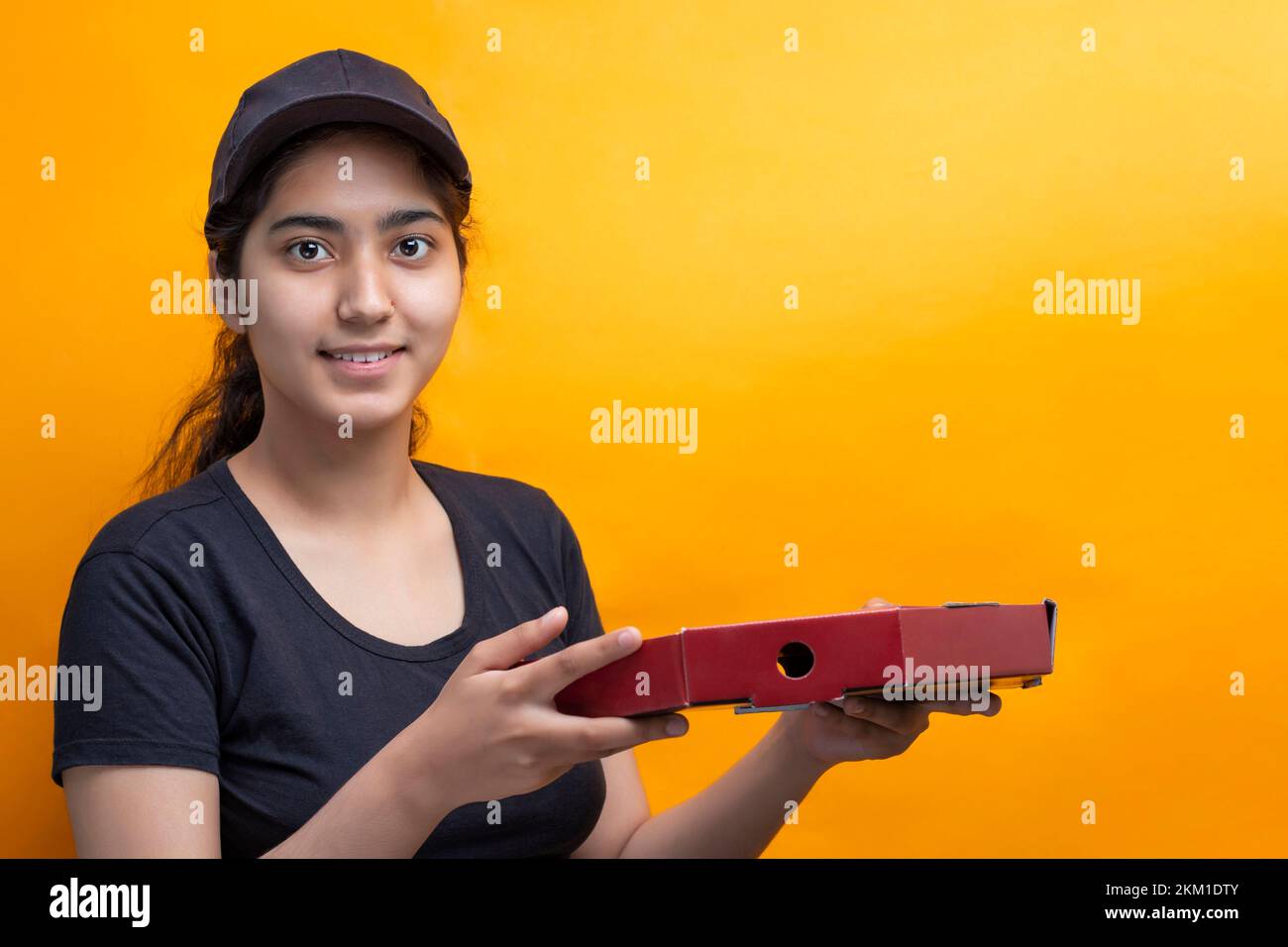 Delivery woman carrying Pizza box against Yellow background Stock Photo Alamy