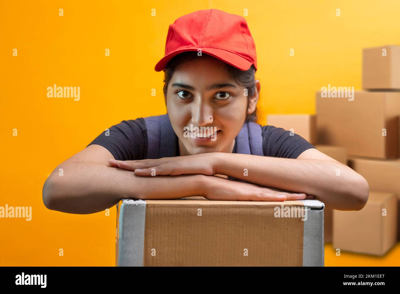 Delivery Woman Lying On Parcel Box and looking at camera Stock Photo