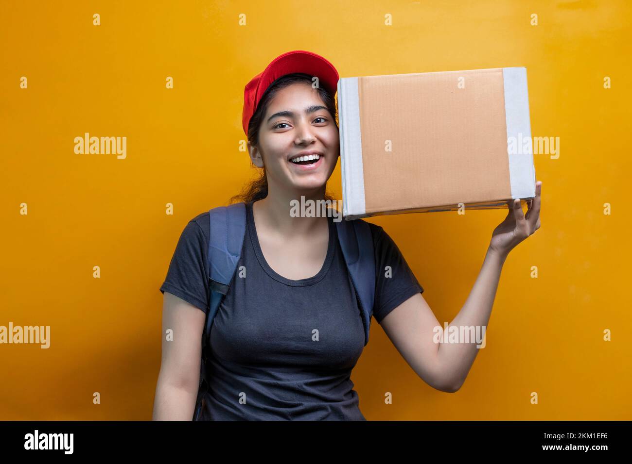 Young delivery woman holding carton box and hearing Stock Photo