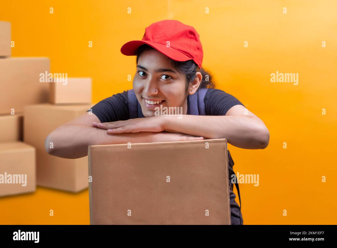 Delivery Woman Lying On Parcel Box and looking at camera Stock Photo