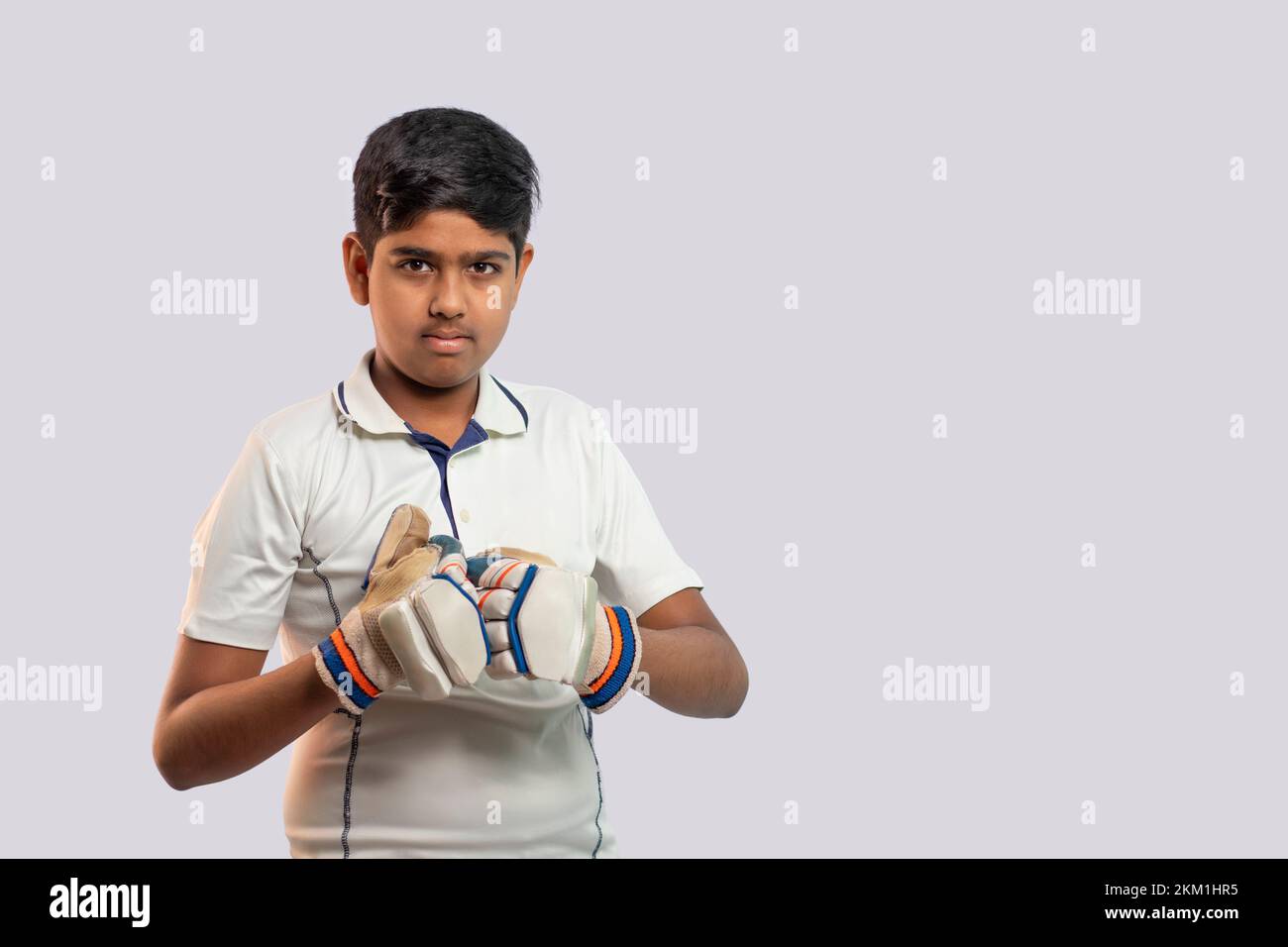 Portrait of young Indian boy wearing hand gloves and getting ready for Cricket game Stock Photo