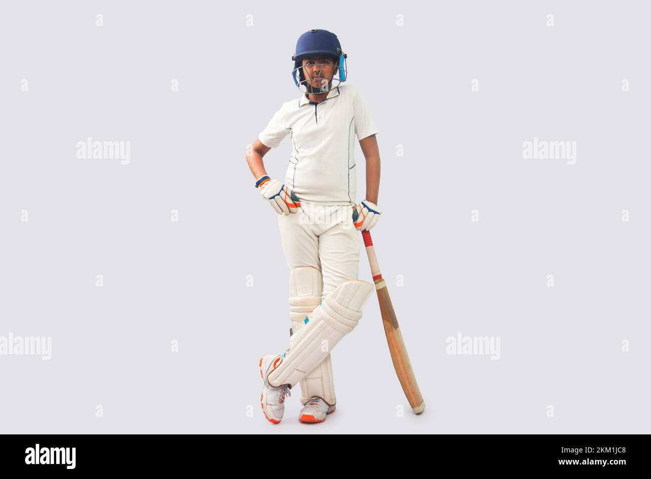 full length of a boy in cricket uniform  standing with bat Stock Photo