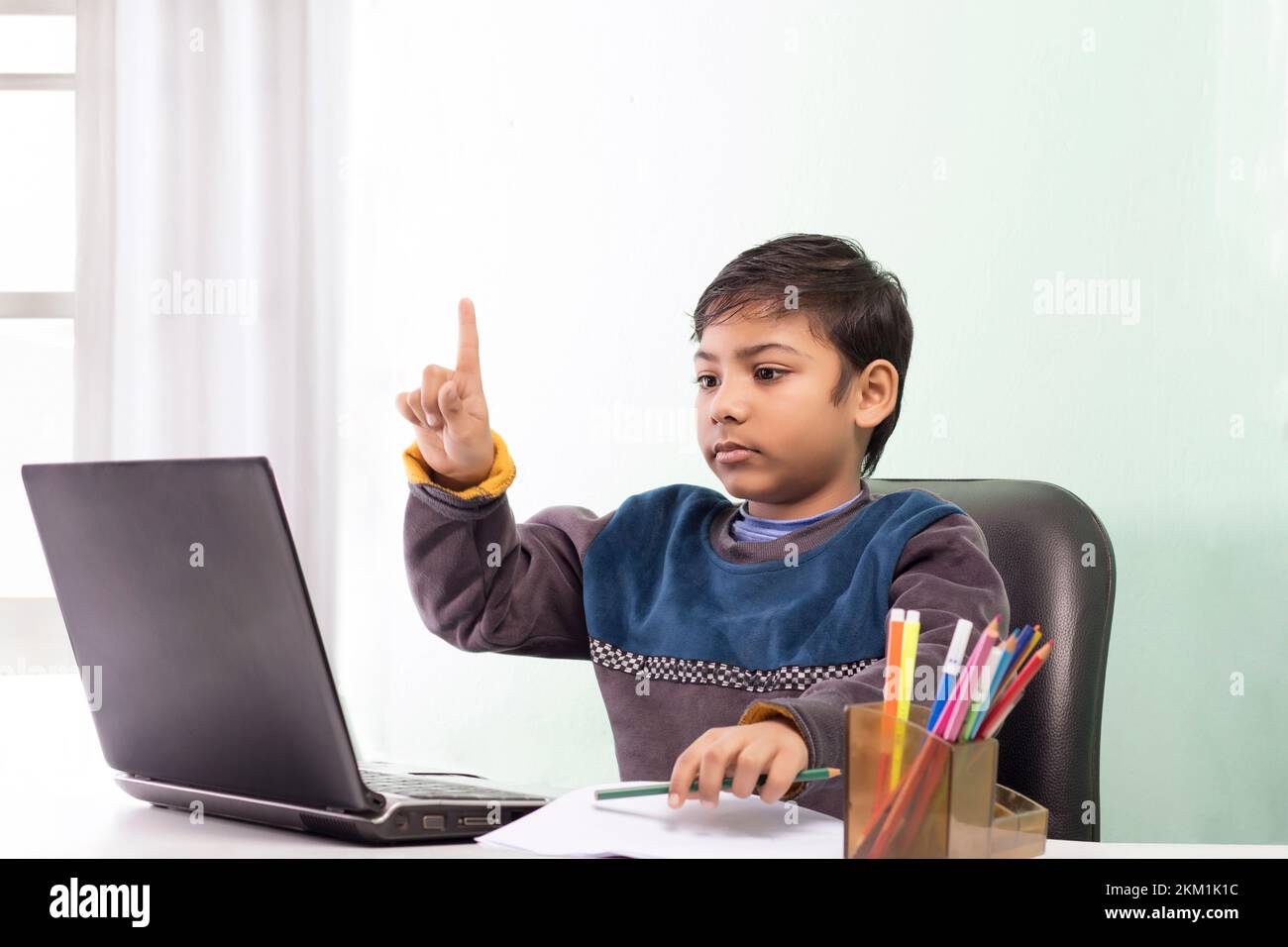 Boy using laptop and waving during video call while homeschooling Stock ...