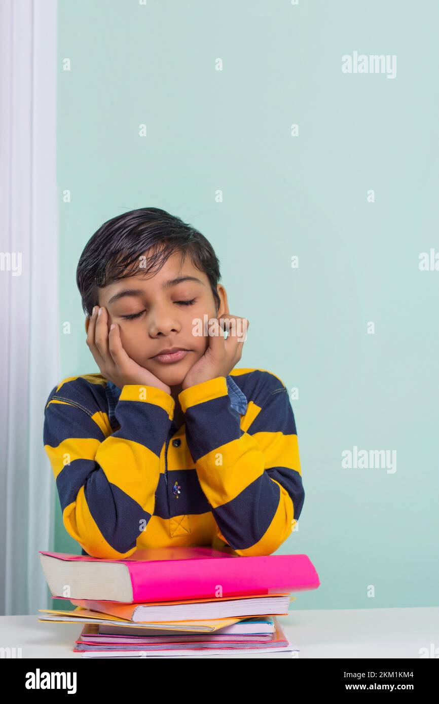 Indian boy with stack of books at home Stock Photo
