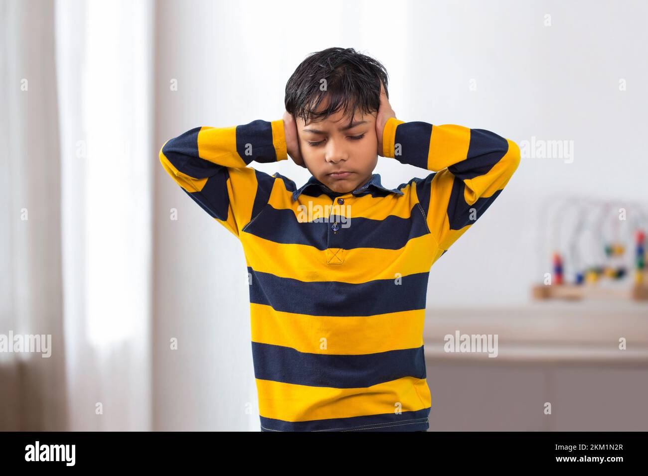 An Indian boy closed eyes covering ears with hands Stock Photo Alamy