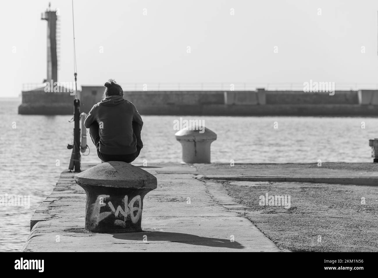 Guy sitting at hte edge of a pier talking on the phone Stock Photo