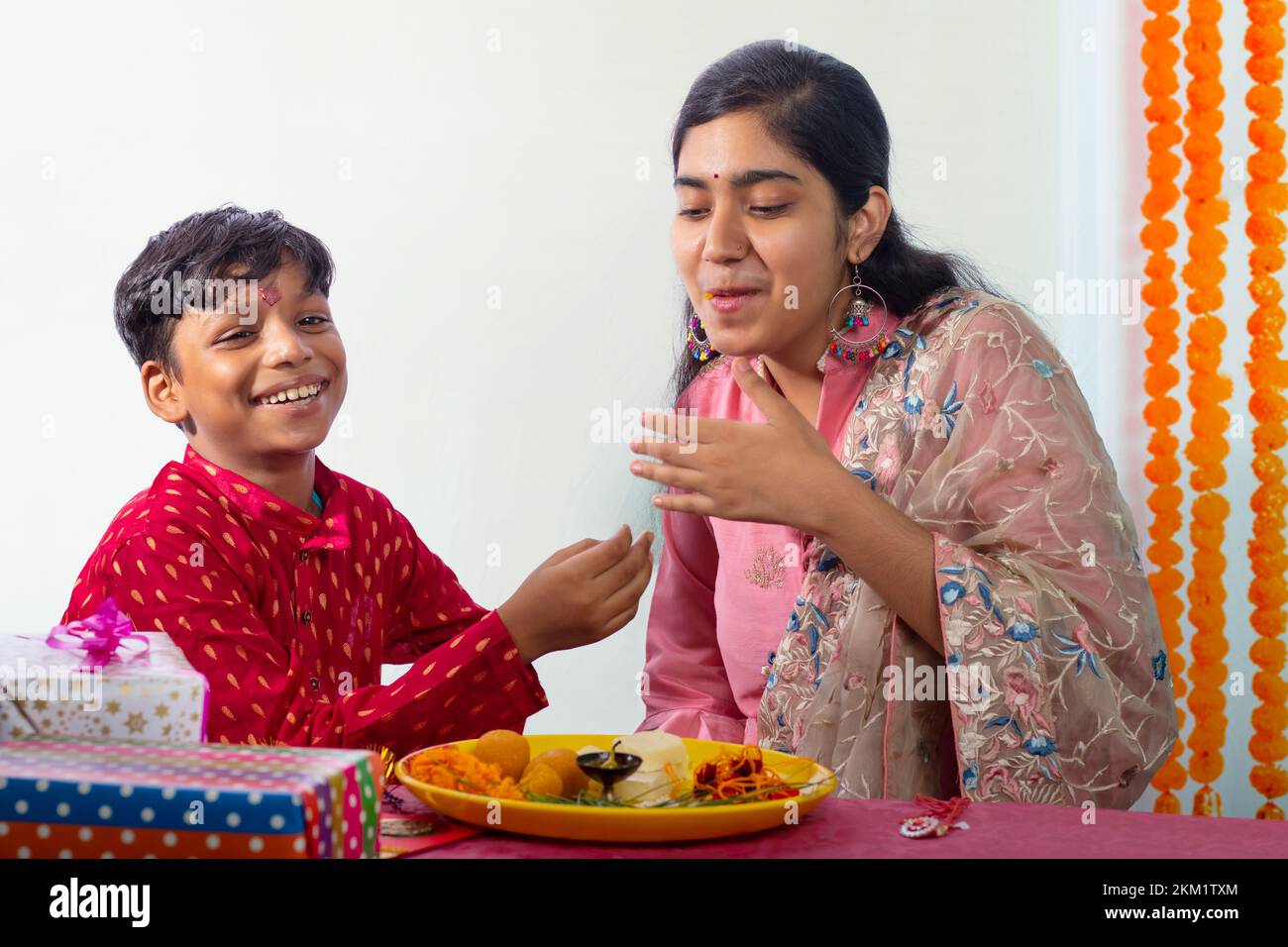 Brother feeding ladoos to his sister on the occasion of Raksha Bandhan Stock Photo