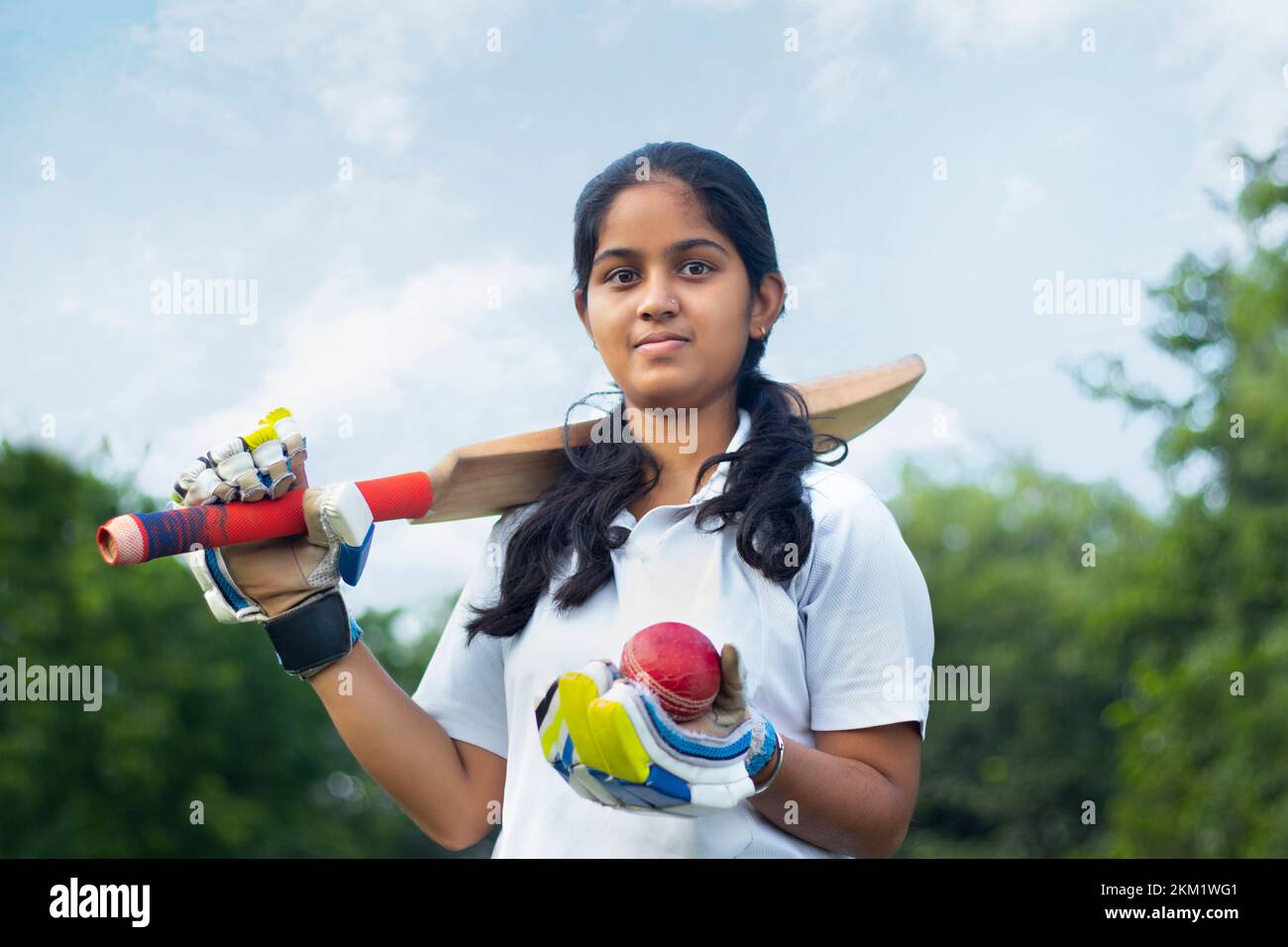 Portrait Of A Female Cricketer Holding A Cricket Bat And A Ball Stock Photo