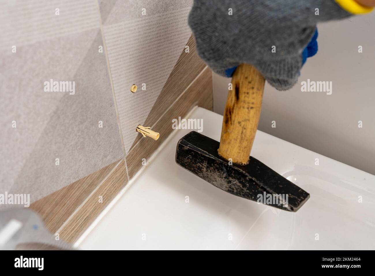 worker's hand inserts a plastic dowel pin into a drilled hole Stock Photo