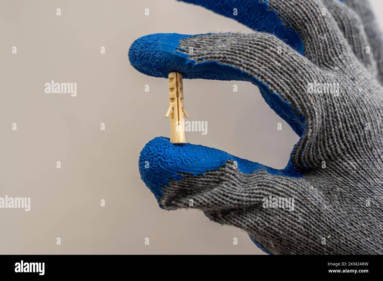 A worker 's hand in a protective glove holds a plastic dowel pin  Stock Photo