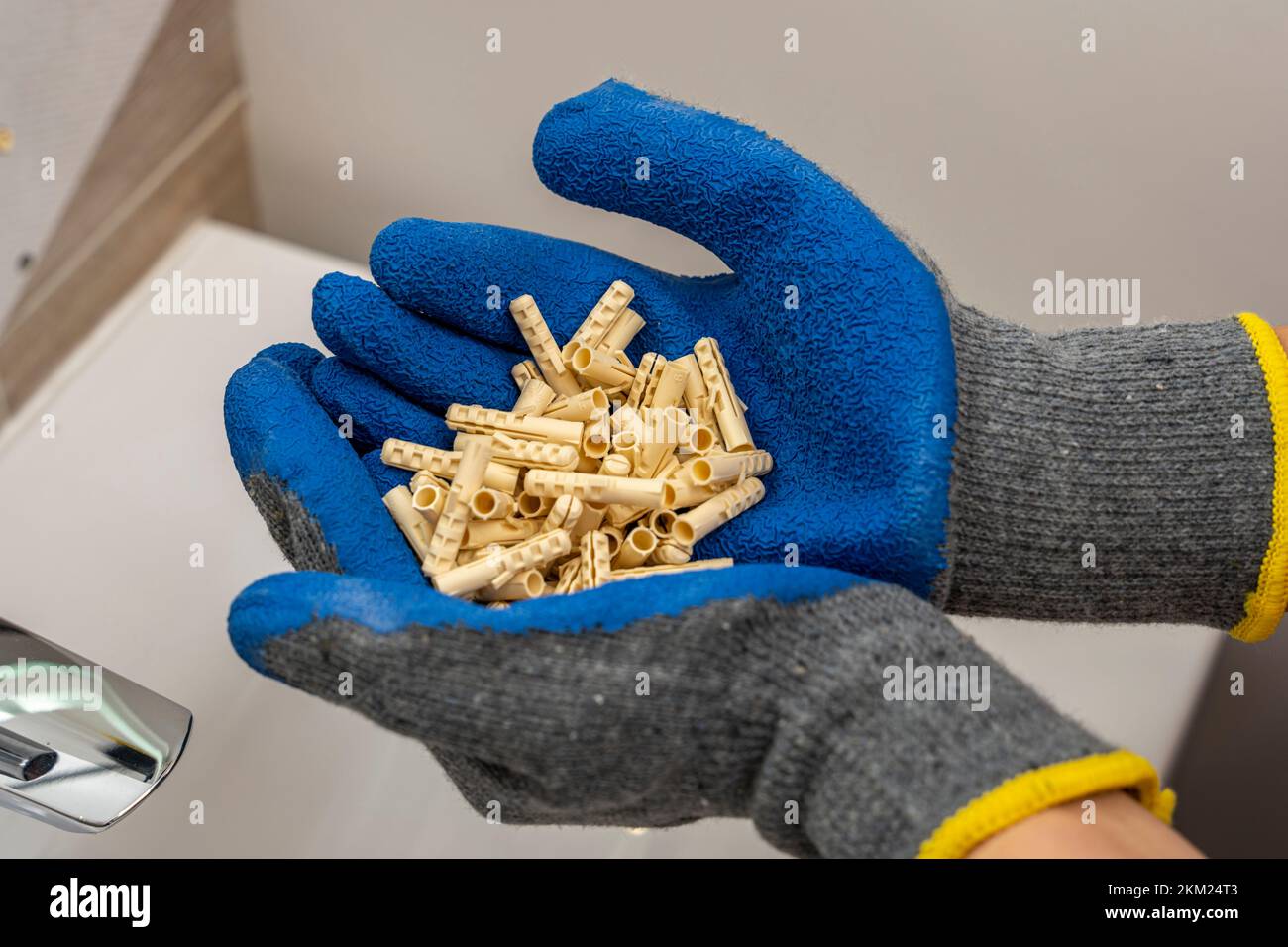 hands of a worker hold in their palms a bunch of plastic dowel pins Stock Photo