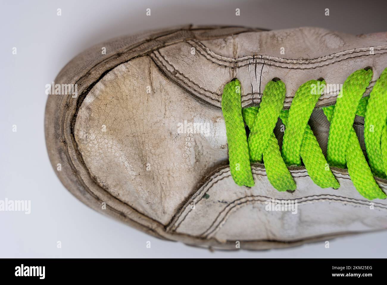 worn old torn white sneakers with colored laces on a white background ...
