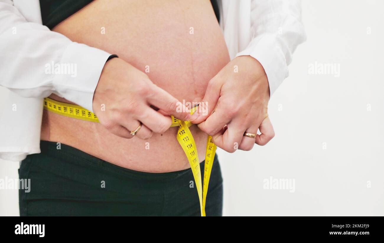 Beautiful pregnant woman measures her stomach, isolated on white Stock Photo
