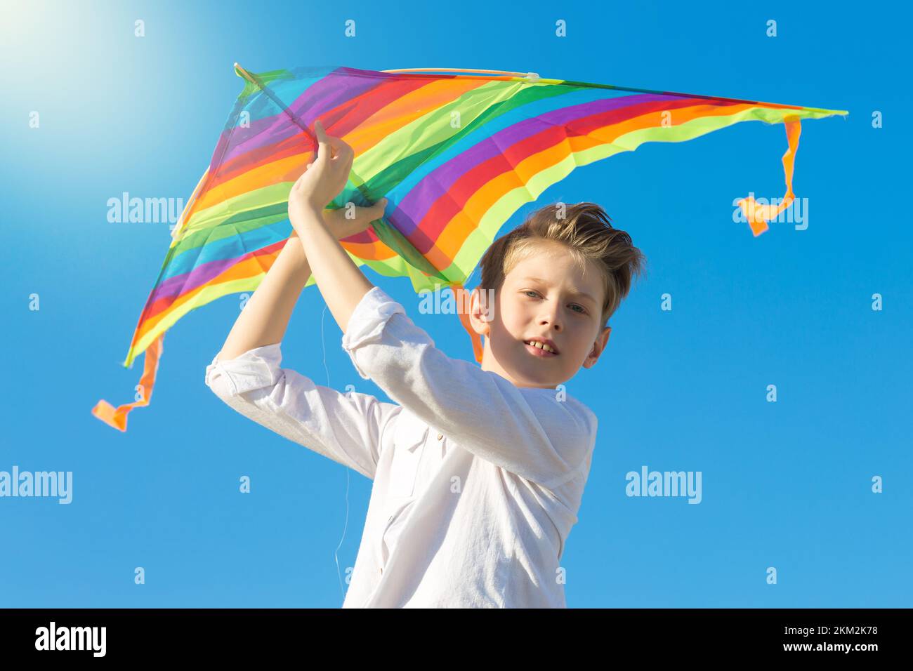 9 year old boy holds bright big kite high above his head. Stock Photo