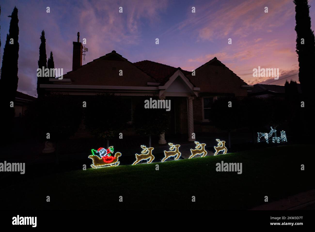 A Santa Claus on a sleigh and reindeer are illuminated  on the front garden of a residential house in Adelaide, South Australia Stock Photo