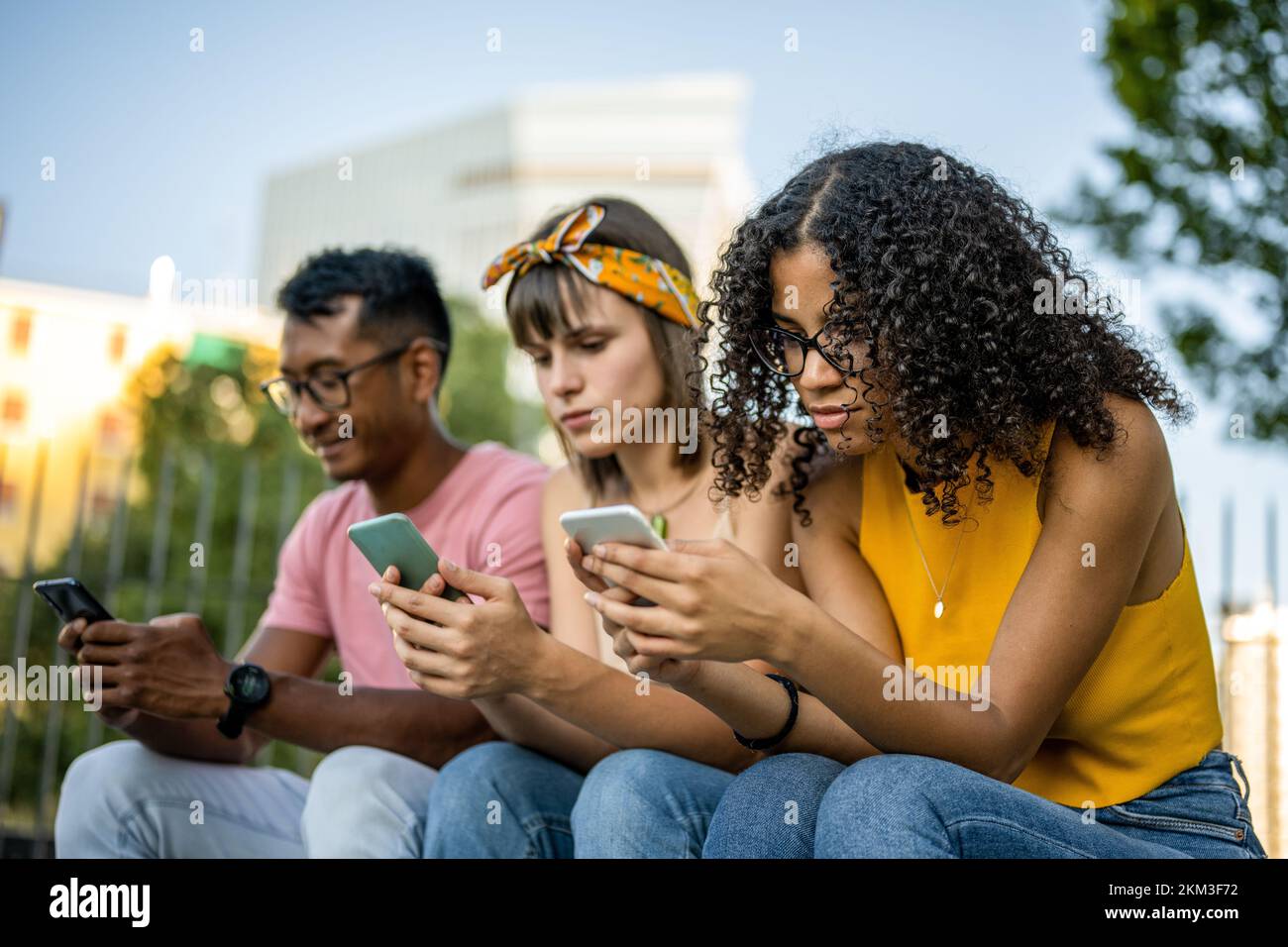 Three young people looking at cell phone, diverse friends spending time on social network Stock Photo