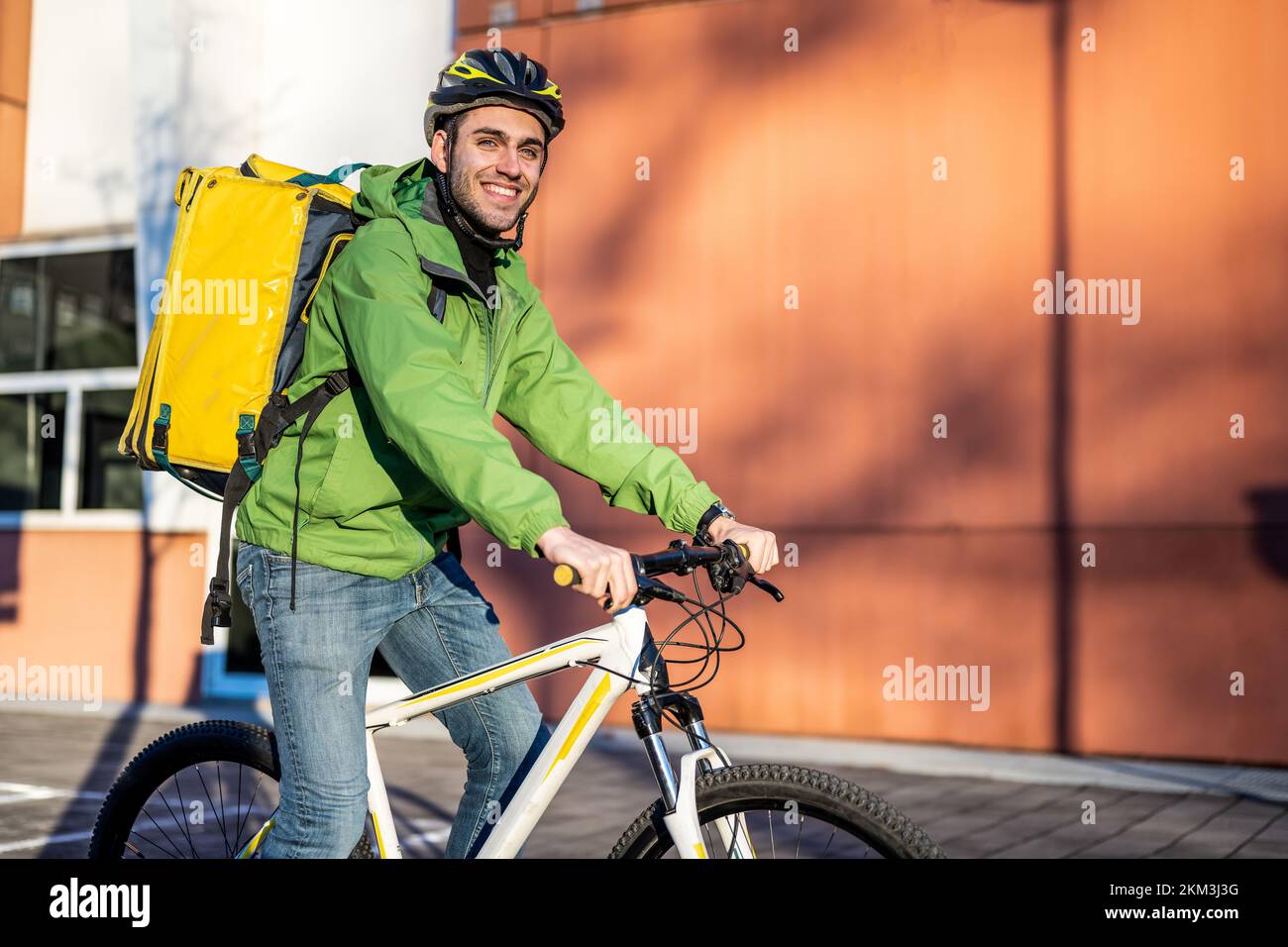 portrait of a smiling fast delivery man on bicycle, food and beverage express delivery service in the city, sustainability way of transportation, envi Stock Photo