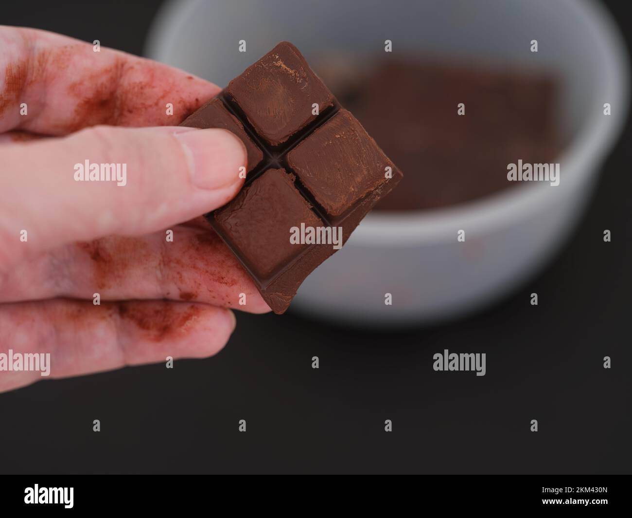 A man taking a piece of melted chocolate out of a bowl of chocolate. Close up. Stock Photo