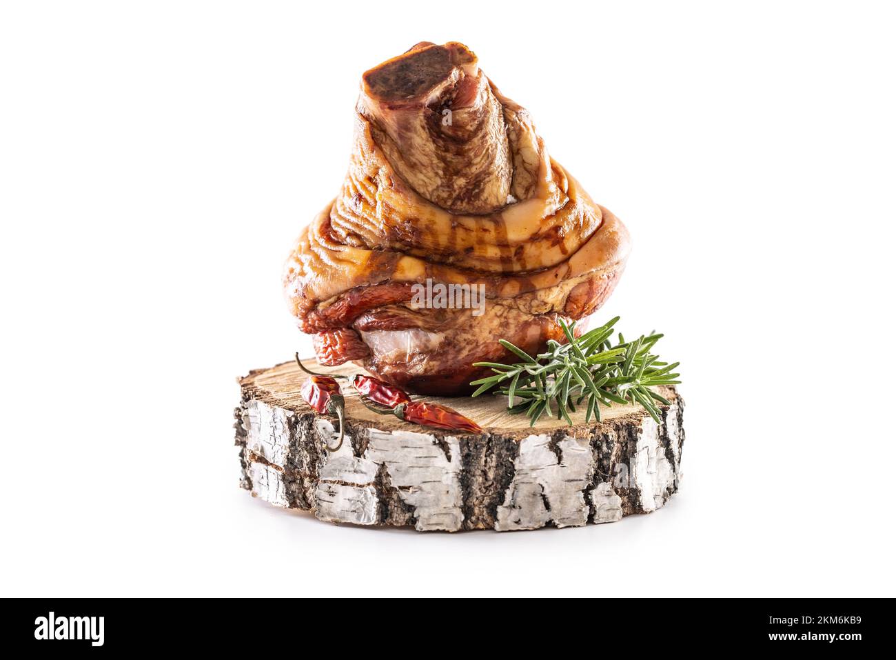 Smoked pork Bavarian knee with rosemary and chili peppers on birch wood - isolated on white. Stock Photo
