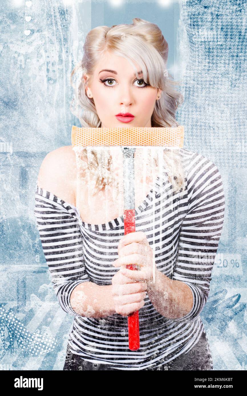 Beautiful female window cleaner using a squeegee to wash a window at a