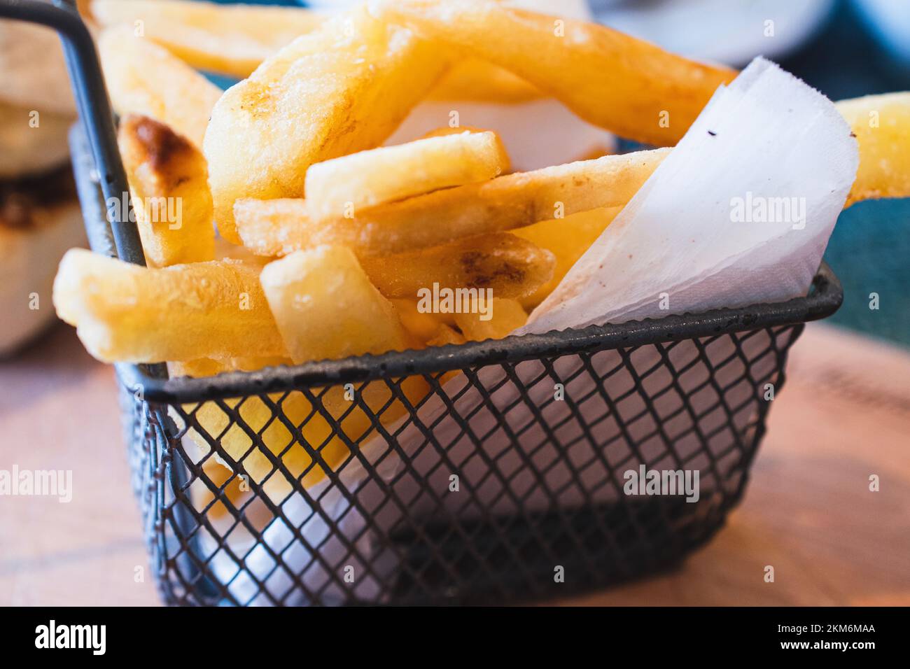 Close up on metal basket filled with yummy French fires, or fried potatoes. Stock Photo
