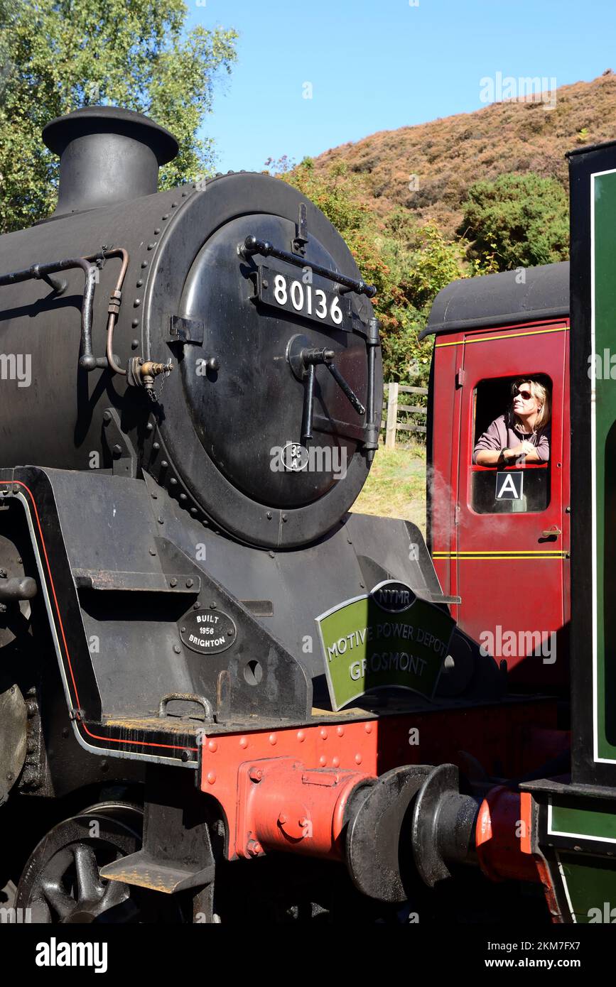 A female passenger on an adjacent train admiring the smokebox of BR Standard class 4 tank engine No 80136 at Goathland station, NYMR. Stock Photo