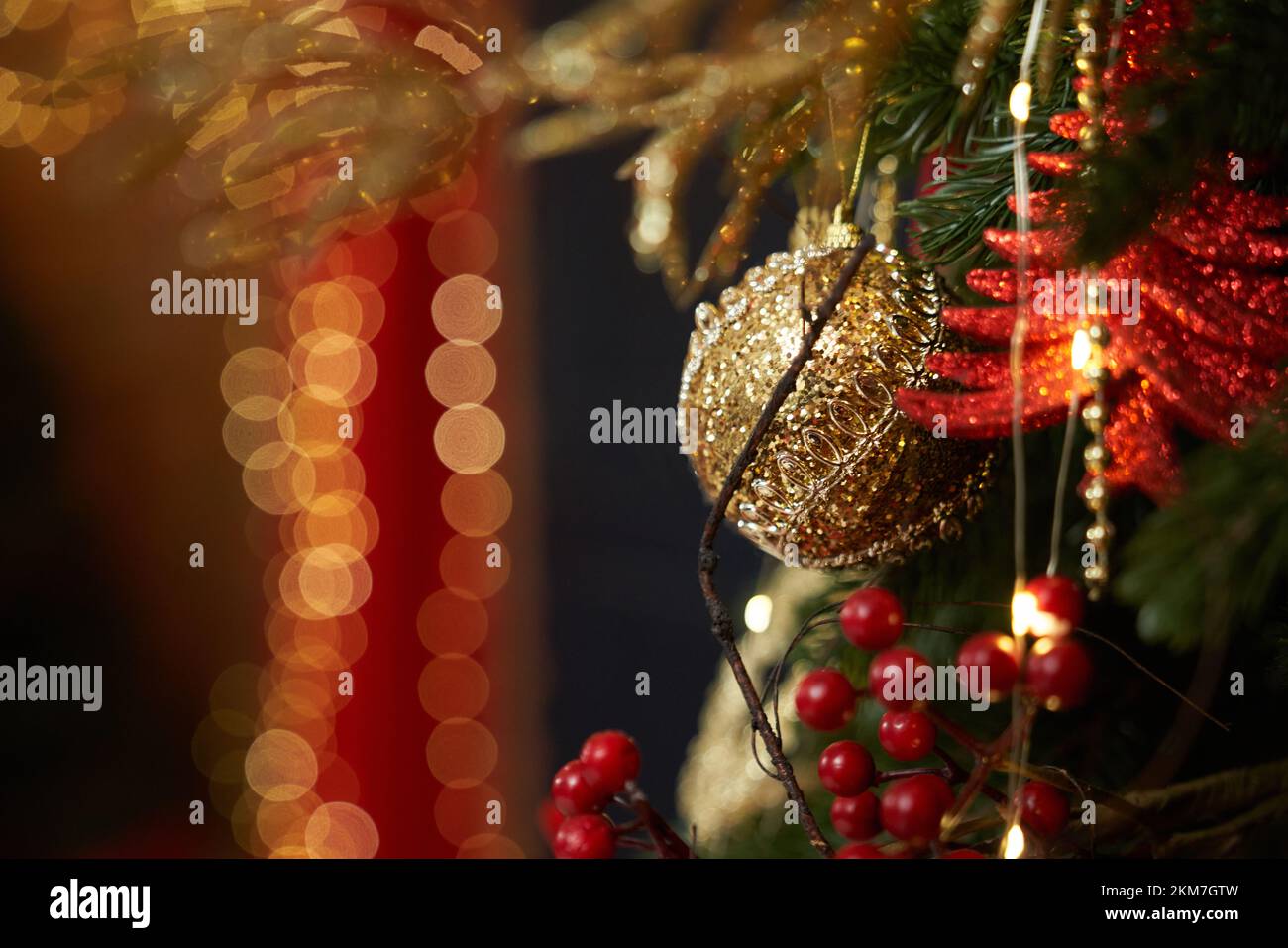 Close up of Christmas tree with garlands and balls sparkling indoors. People celebrating, expecting first New Year in festive decorated room. Concept Stock Photo
