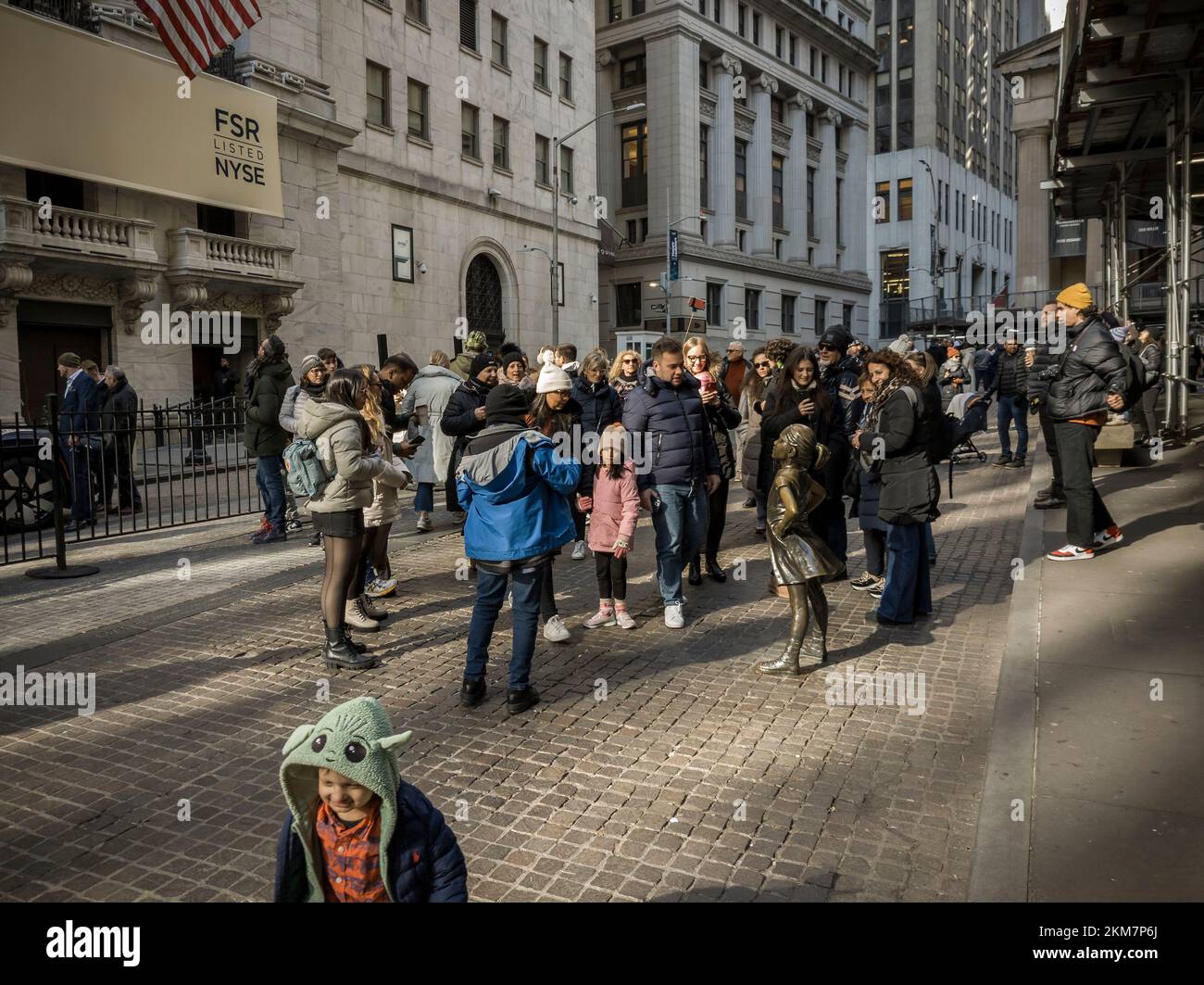 Tourists flock to the bronze statue, 'The Fearless Girl' by the artist Kristen Visbal in front of the New York Stock Exchange on Tuesday, November 22, 2022. (© Richard B. Levine) Stock Photo